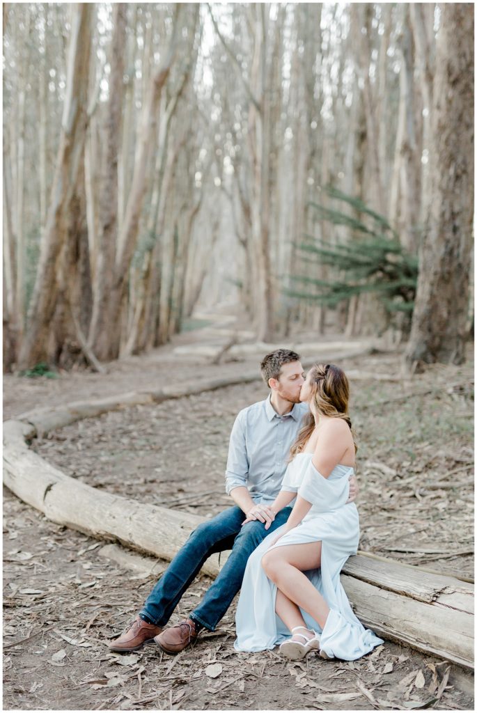 engaged couple sitting on lovers lane log and kissing